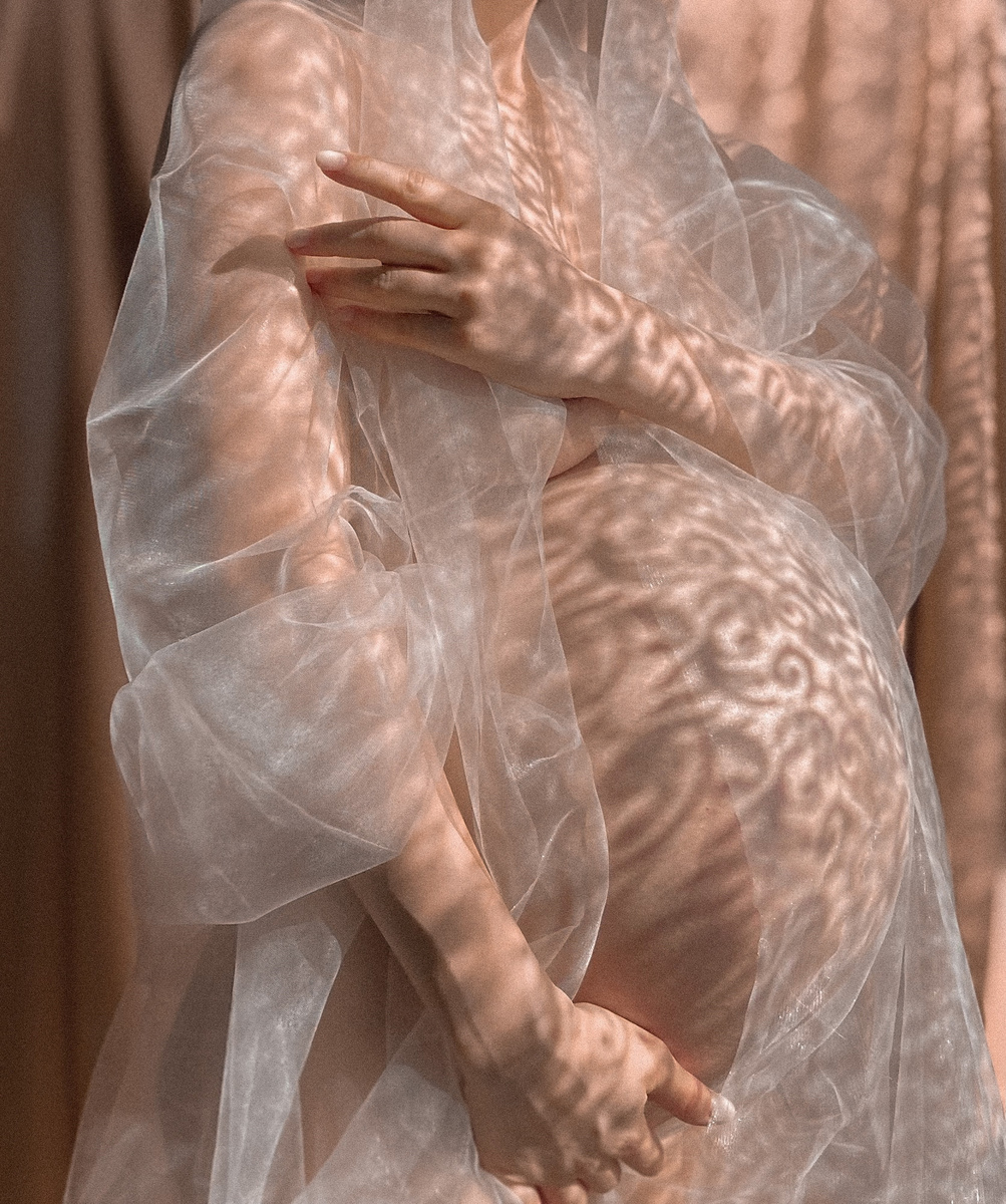 Crop pregnant woman in transparent cloth